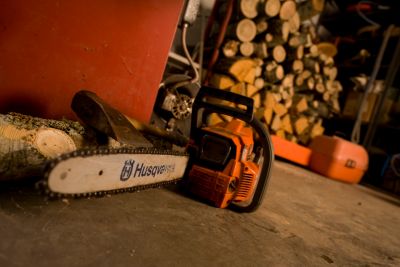 Husqvarna chainsaw with pile of wood.