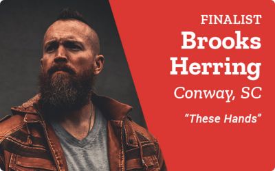 Finalist. Brooks Herring. Conway, South Carolina. These Hands. A promotional banner featuring a portrait of Brooks Herring with a beard and mohawk hairstyle standing in a dimly lit setting.