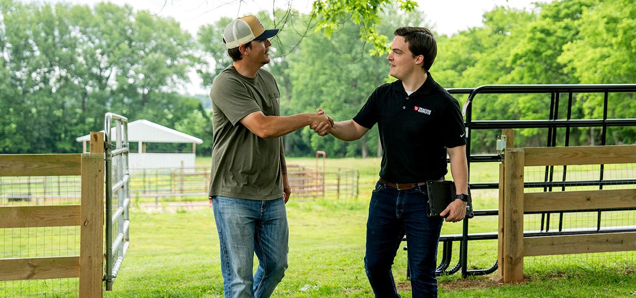 A Tractor Supply specialist meeting with a customer at a farm.