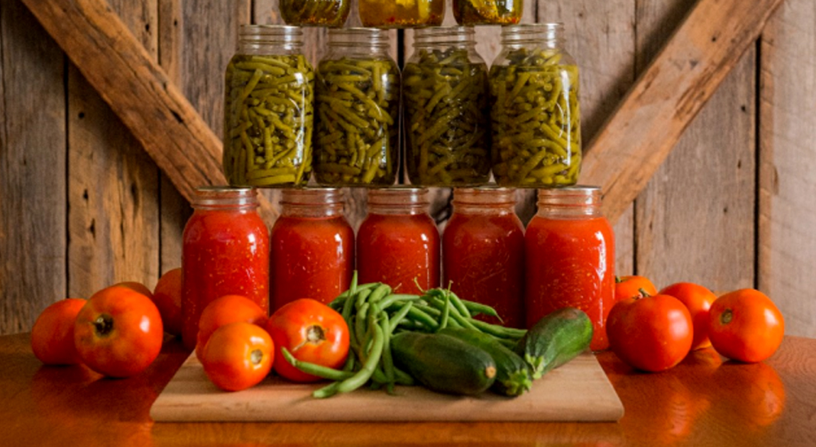 Jars of canned vegetables with fresh tomatoes and peppers.
