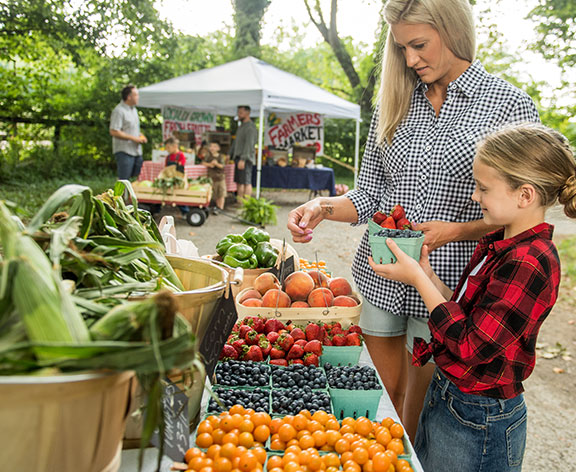 Family shopping for fresh produce at a Tractor Supply Harvest Fest community market.