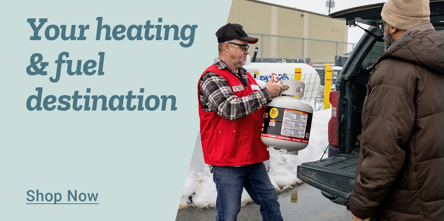 Promotional banner with a light blue background on the left and a photo on the right. Large blue text on the left reads: Your heating &amp; fuel destination. Below is underlined blue text that reads: Shop Now. On the right side, a Tractor Supply Co. team member wearing a red vest and black cap is handing a white propane tank to a customer at the open back of a pickup truck. Snow is visible on the ground, and a store building and parking lot equipment appear in the background, indicating a winter setting.