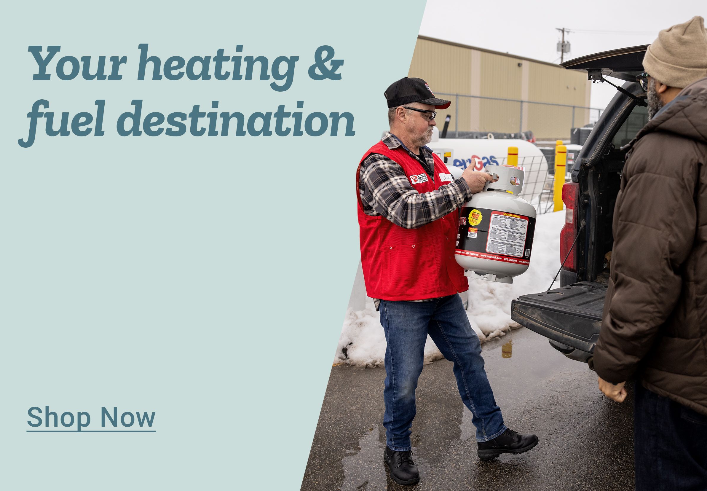 Promotional banner with a light blue background on the left and a photo on the right. Large blue text on the left reads: Your heating &amp; fuel destination. Below is underlined blue text that reads: Shop Now. On the right side, a Tractor Supply Co. team member wearing a red vest and black cap is handing a white propane tank to a customer at the open back of a pickup truck. Snow is visible on the ground, and a store building and parking lot equipment appear in the background, indicating a winter setting.