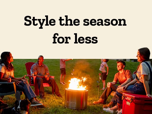 Style the season for less. A promotional banner for outdoor furniture and decor. The left side of the image shows a wooden porch swing,a rocking chair,and potted orange mums on a stone patio. The right side shows a family sitting around a fire pit in a backyard at dusk.